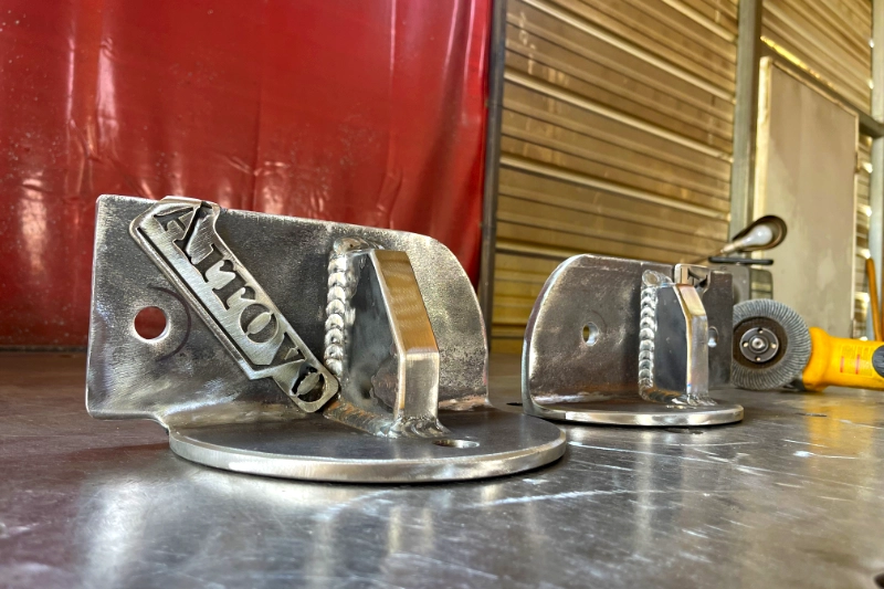 Polished aluminium brackets on the shop bench, the Arroyo name cut into the face of one